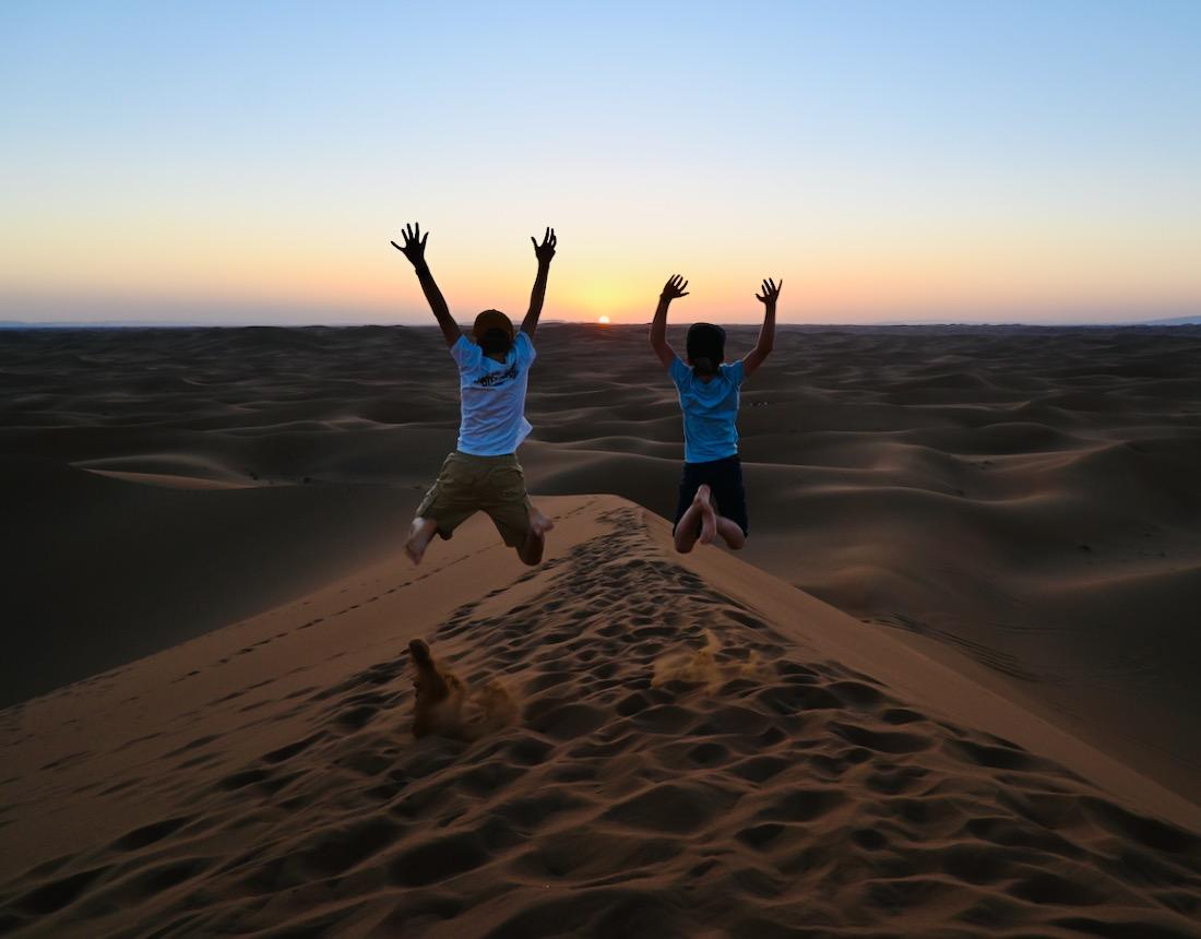 Flo und Ben springen im Sonnenuntergang in Marokko in der Sahara