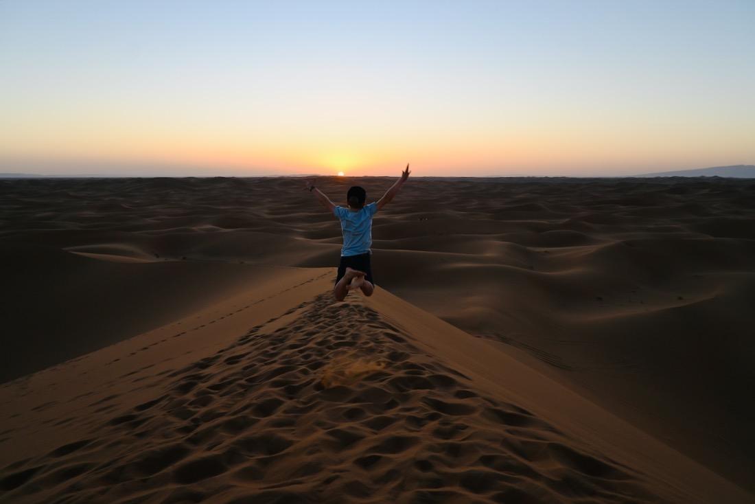 Benjamin springt in der Sahara im Sonnenuntergang