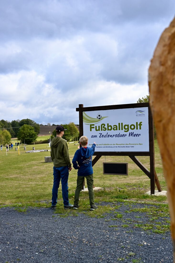 Benni und Flo vor Fußballgolf-Schild Am Bio-Seehotel Zeulenroda
