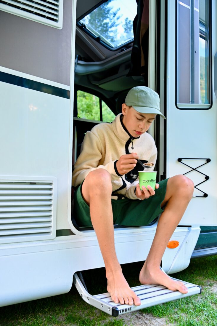 Flo isst ein Müsli auf der Camper Treppe
