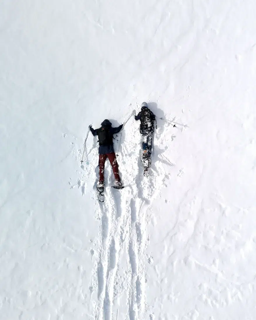 Flo und Ben liegen mit Schneeschuhen im Schnee