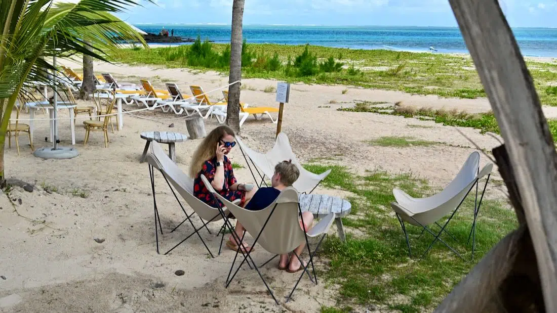 Melanie und Ben telefonieren mit eSIM am Strand com C Mourouk Rodrigues
