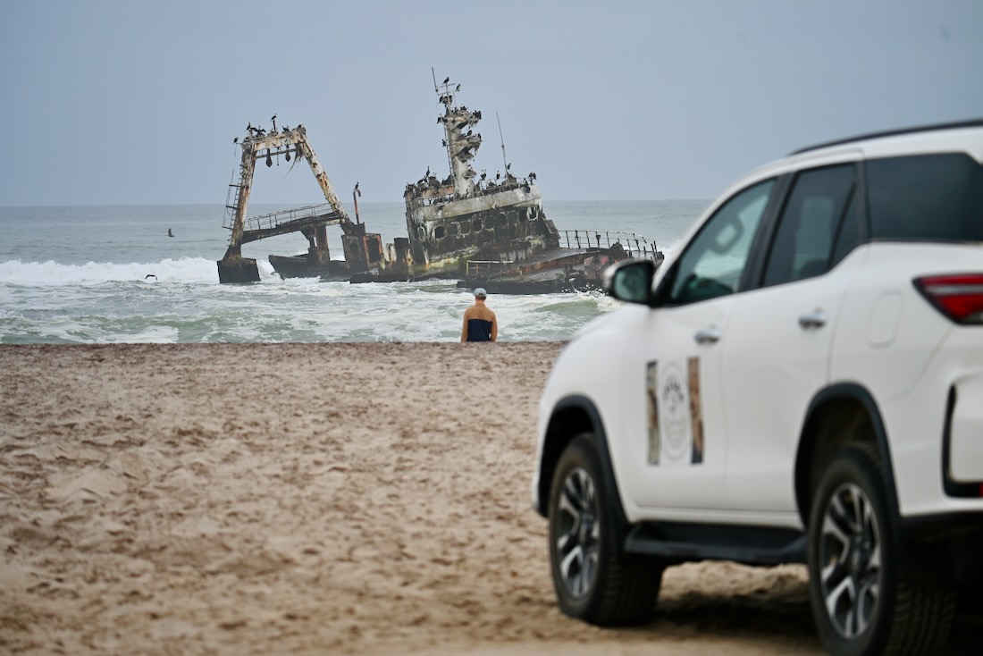 Flo steht vor einem Wrack an der Sceleton Coast in Namibia