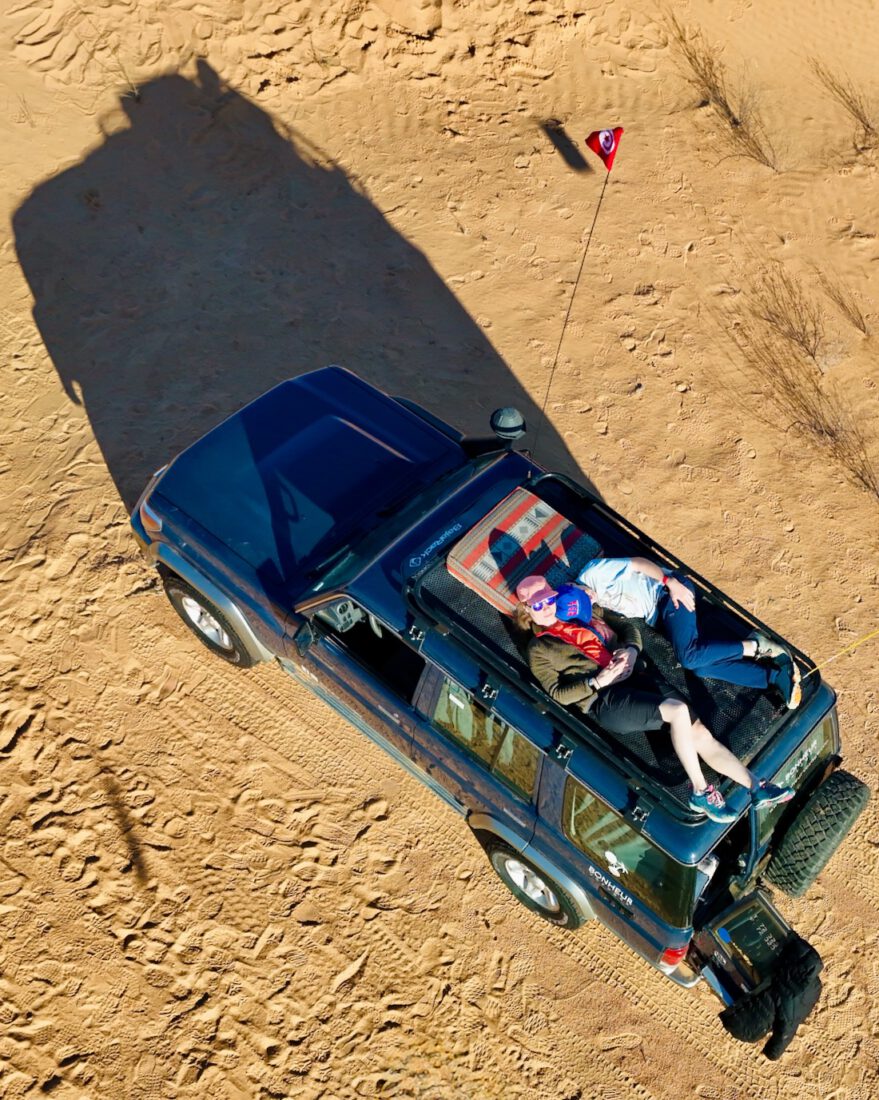Melanie und Ben liegen in der Sonne auf dem 4x4 Auto