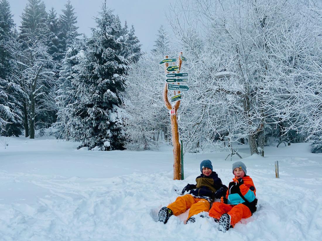 Flo und Ben von Fravely am Wegweiser auf der Bank am Fichtelberg